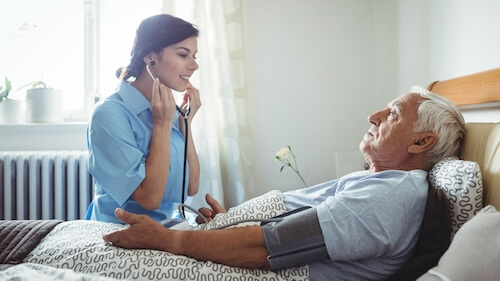 Nurse wearing a blue uniform holding a stethoscope with a patient.